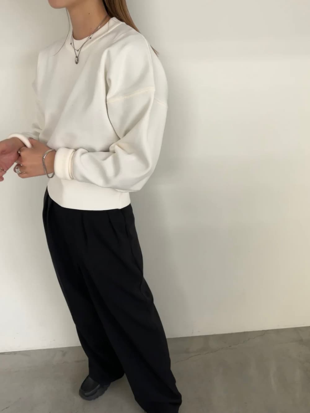 ホワイト系のニット/セーター、ブラック系のスラックスを着用したレディースの冬コーディネートの3枚目の写真