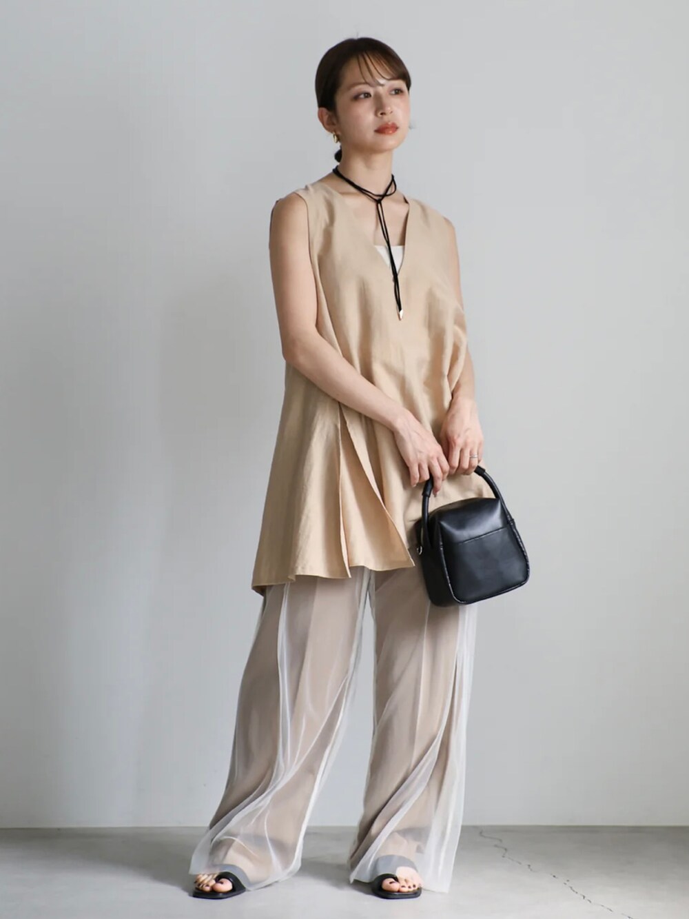 ベージュ系のベスト、ホワイト系のキャミソール、ホワイト系のその他パンツを着用したレディースの夏コーディネートの3枚目の写真