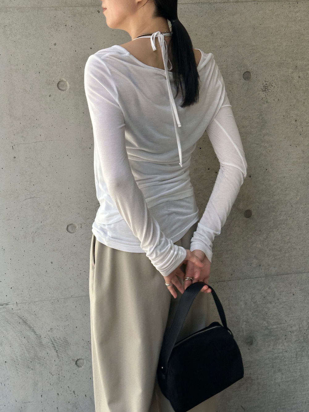 ホワイト系のTシャツ/カットソー、ブラック系のハンドバッグ、ベージュ系のスラックスを着用したレディースの秋コーディネートの5枚目の写真