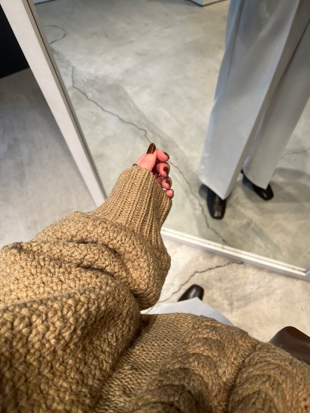 ベージュ系のニット/セーター、ホワイト系のスラックス、ブラウン系のハンドバッグを着用したレディースの冬コーディネートの4枚目の写真