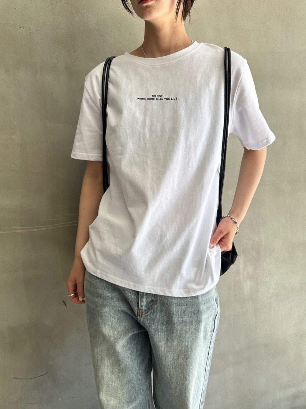 ホワイト系のTシャツ/カットソー、ブルー系のデニムパンツ、ブラック系のバックパック/リュックを着用したレディースの春コーディネートの4枚目の写真