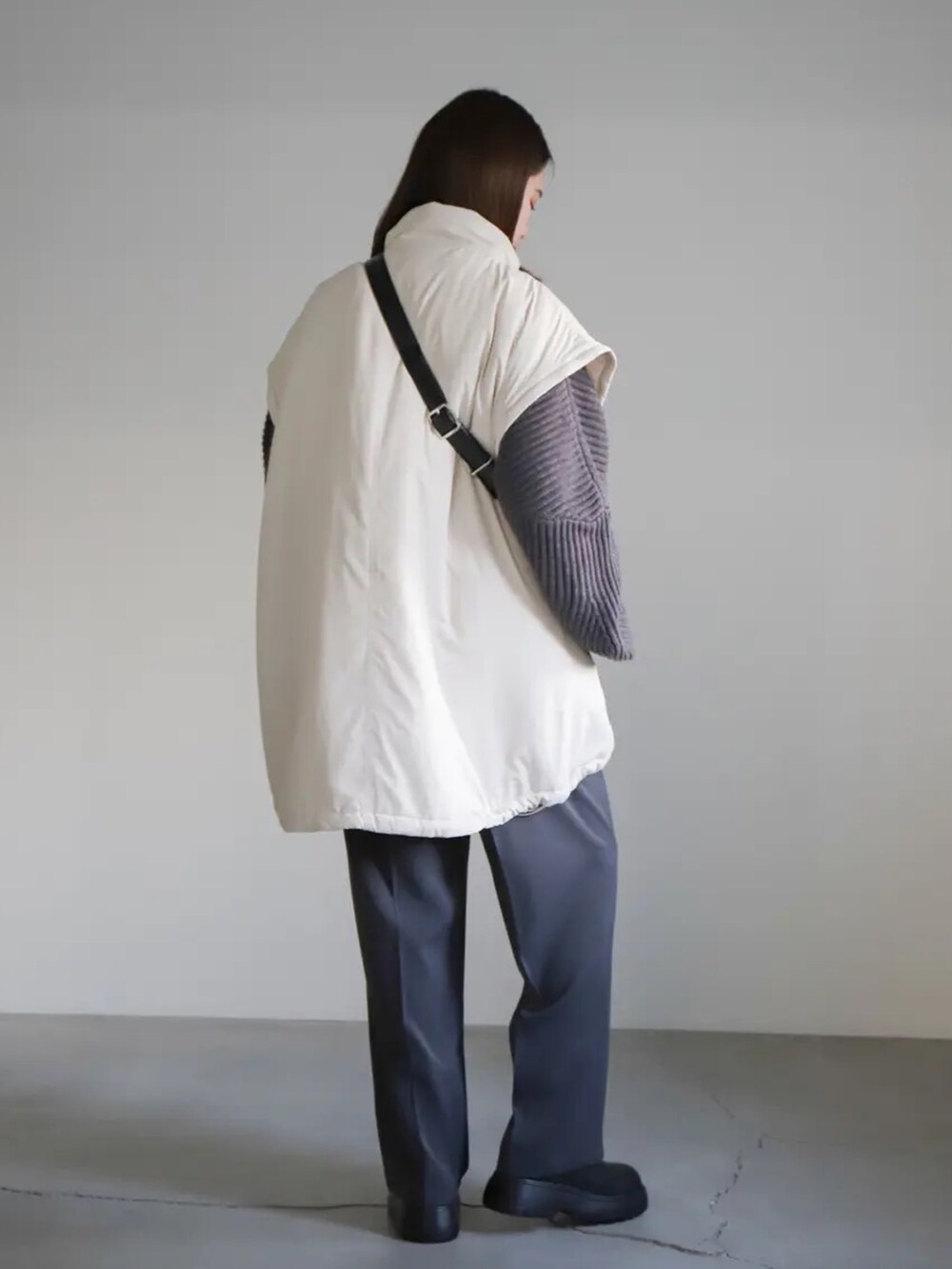 グレー系のニット/セーター、グレー系のスラックス、ホワイト系のダウンジャケット/コートを着用したレディースの冬コーディネートの4枚目の写真