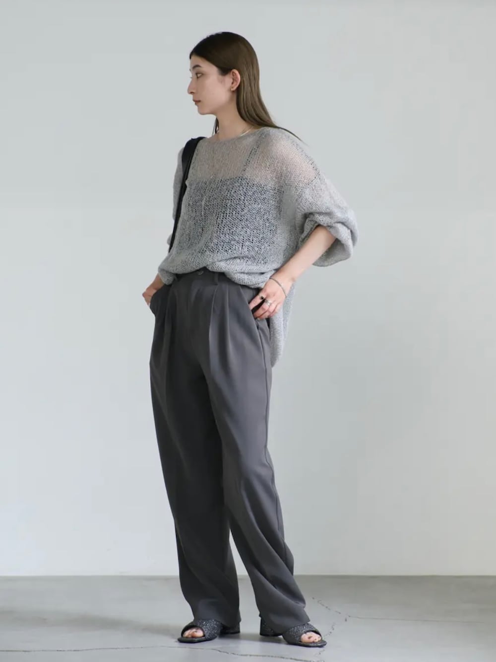 グレー系のニット/セーター、グレー系のスラックス、ブラック系のサンダルを着用したレディースの夏コーディネートの4枚目の写真