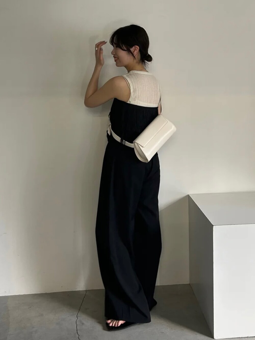 ブラック系のベスト、ホワイト系のニット/セーター、ブラック系のスラックスを着用したレディースの春コーディネートの2枚目の写真