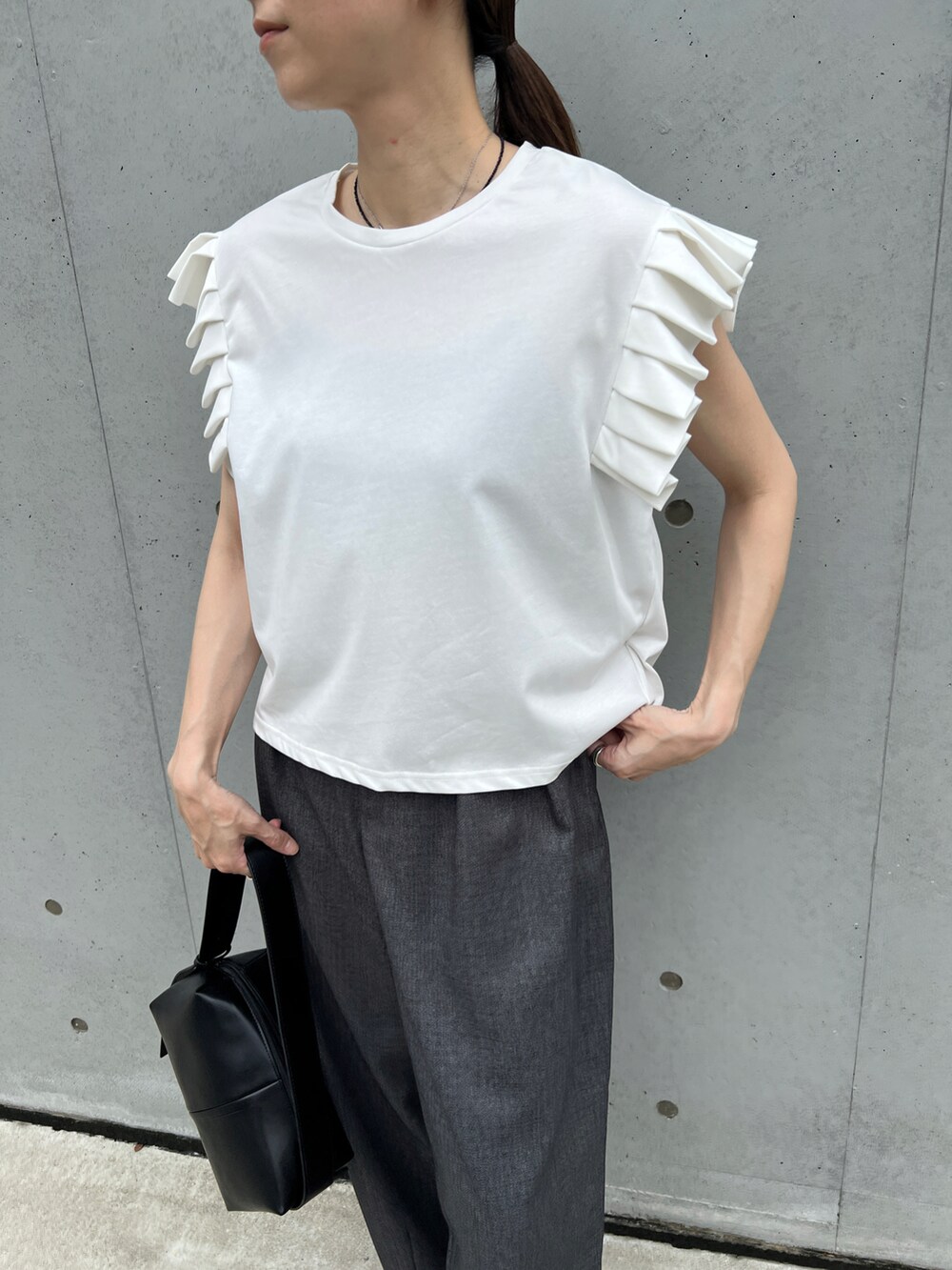 ブラック系のショルダーバッグ、ホワイト系のTシャツ/カットソー、グレー系のスラックスを着用したレディースの夏コーディネートの3枚目の写真