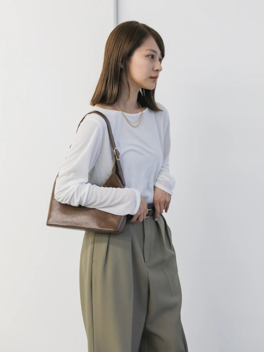 ホワイト系のTシャツ/カットソー、ベージュ系のスラックス、ブラウン系のハンドバッグを着用したレディースの冬コーディネートの4枚目の写真