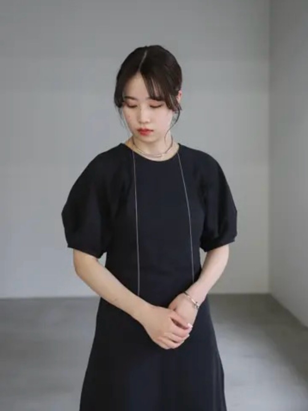 ブラック系のワンピース、シルバー系のハンドバッグ、シルバー系のネックレスを着用したレディースの夏コーディネートの4枚目の写真