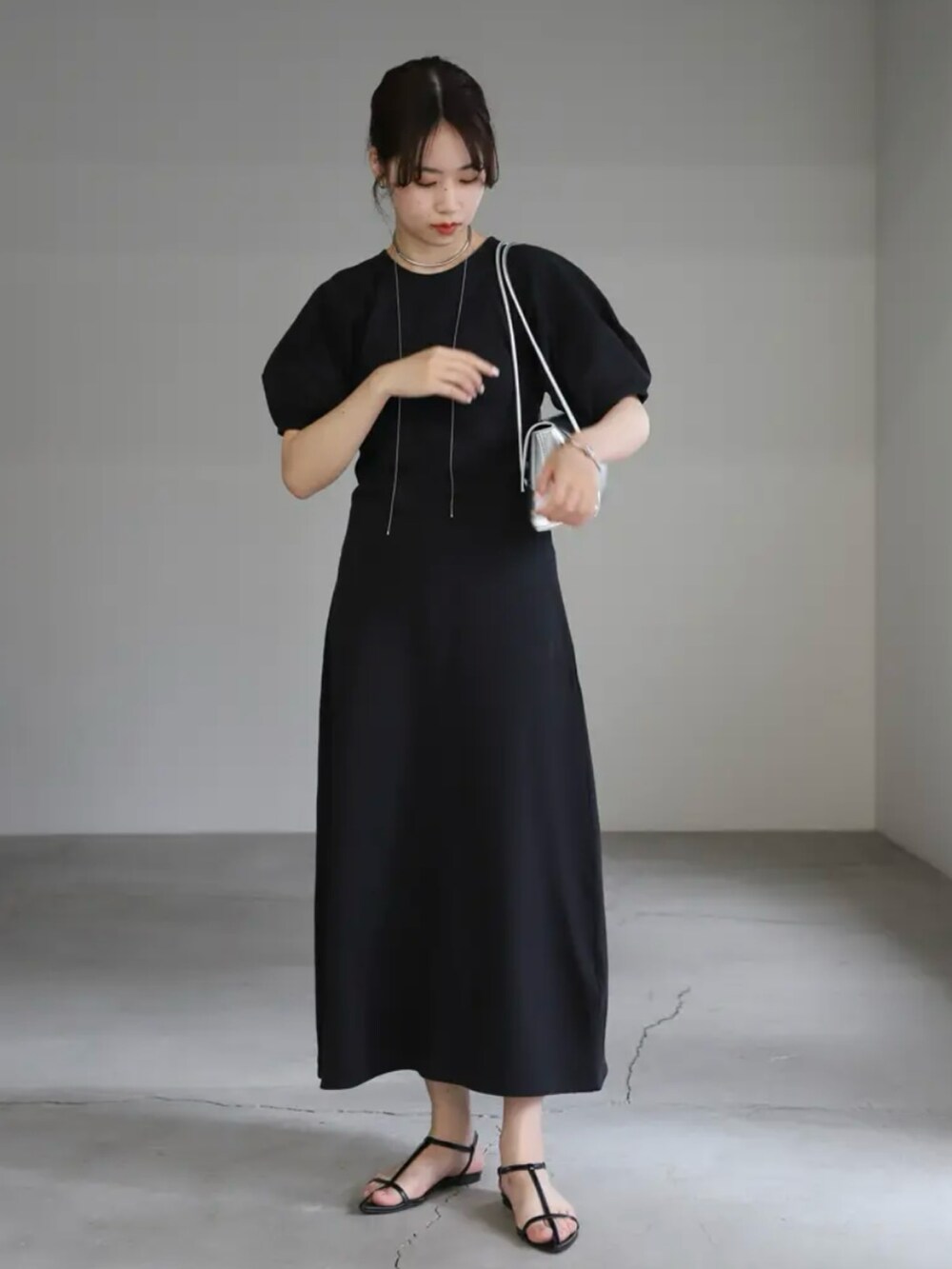 ブラック系のワンピース、シルバー系のハンドバッグ、シルバー系のネックレスを着用したレディースの夏コーディネートの5枚目の写真