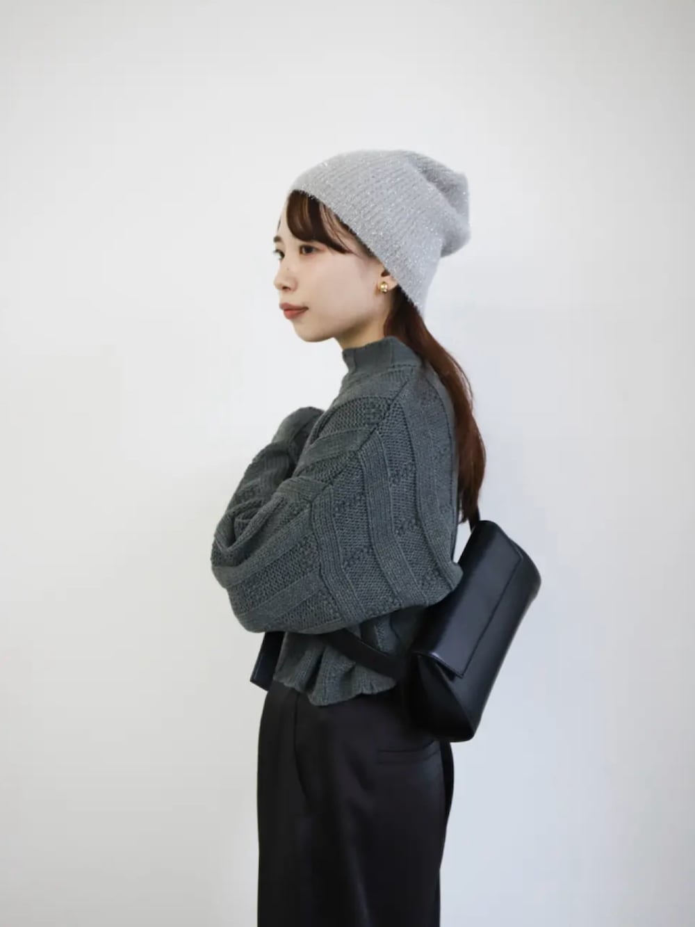 ブラック系のスラックス、ブラック系のショルダーバッグ、グレー系のニット/セーターを着用したレディースの冬コーディネートの4枚目の写真