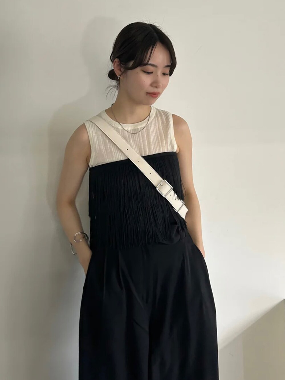 ブラック系のベスト、ホワイト系のニット/セーター、ブラック系のスラックスを着用したレディースの春コーディネートの4枚目の写真