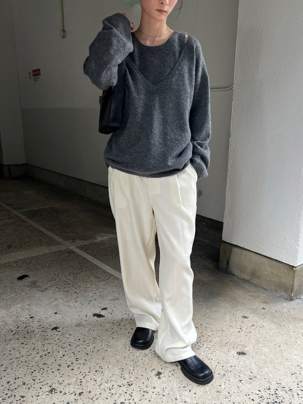 グレー系のニット/セーター、ベージュ系のスラックス、ブラック系のショルダーバッグを着用したレディースの秋コーディネートの2枚目の写真