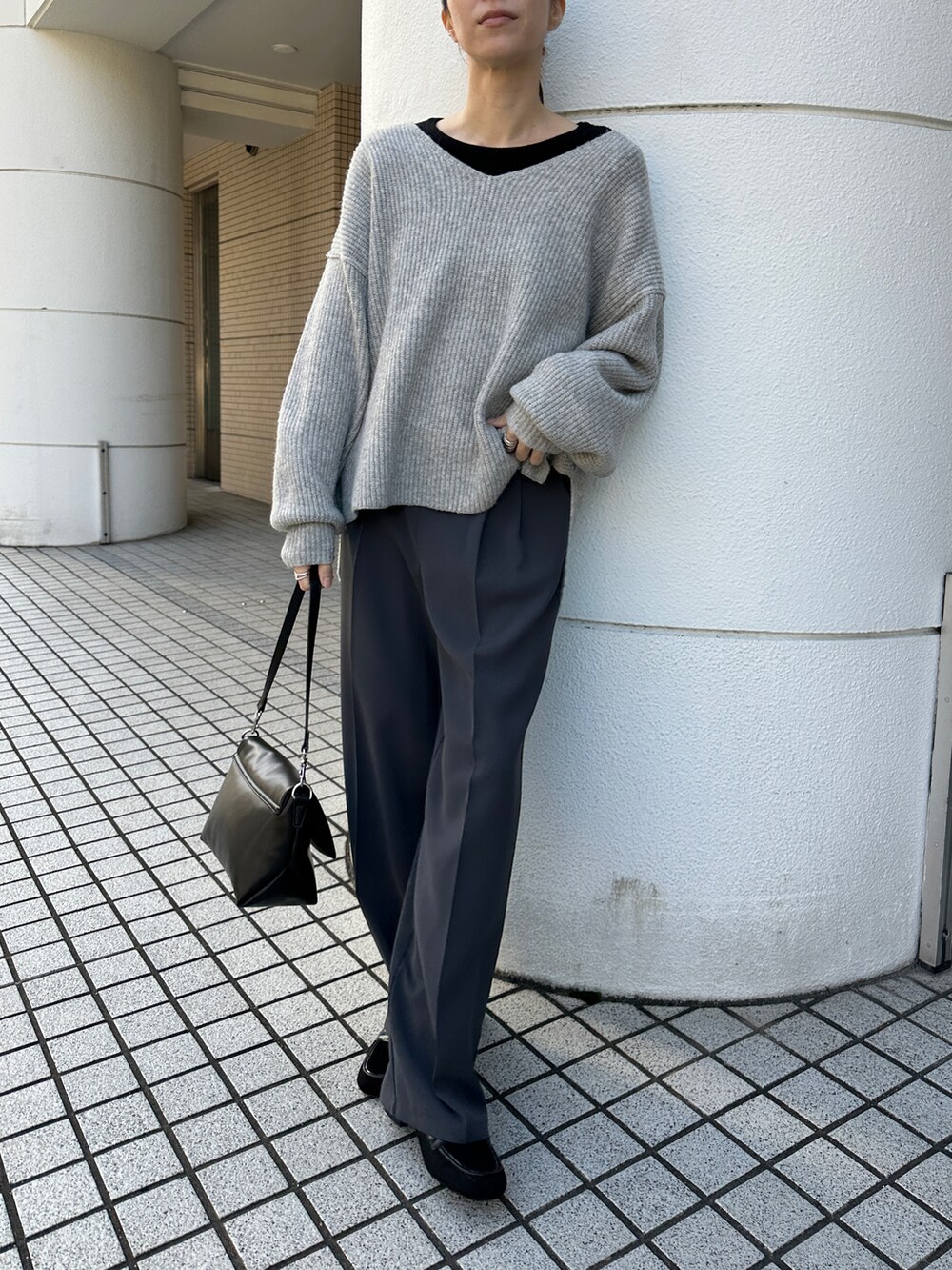 グレー系のニット/セーター、ブラック系のTシャツ/カットソー、グレー系のスラックスを着用したレディースの冬コーディネートの2枚目の写真