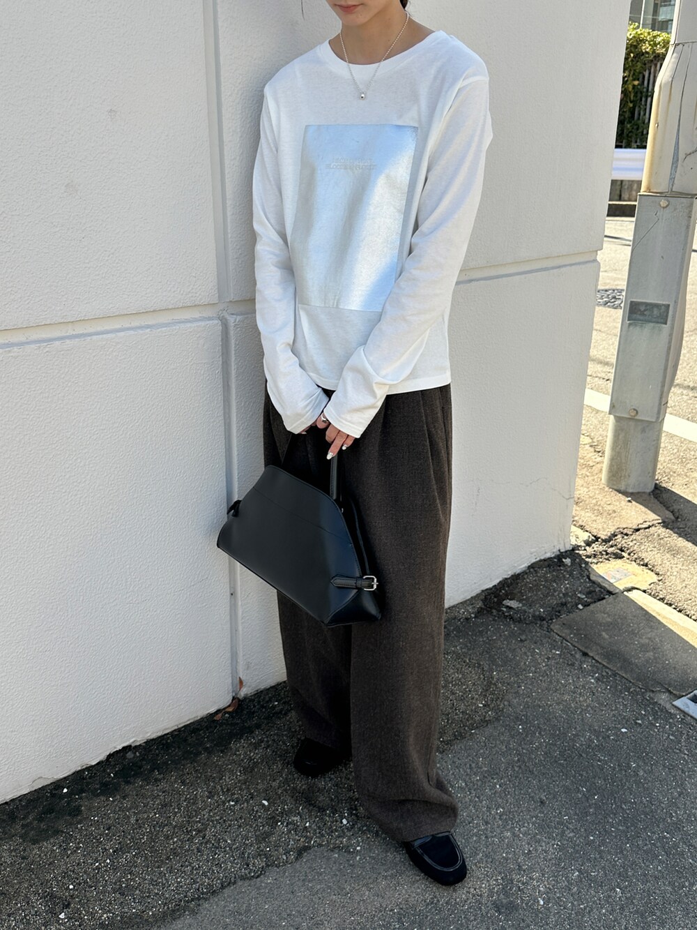 ホワイト系のTシャツ/カットソー、ブラック系のハンドバッグ、ブラック系のローファーを着用したレディースの秋コーディネートの2枚目の写真