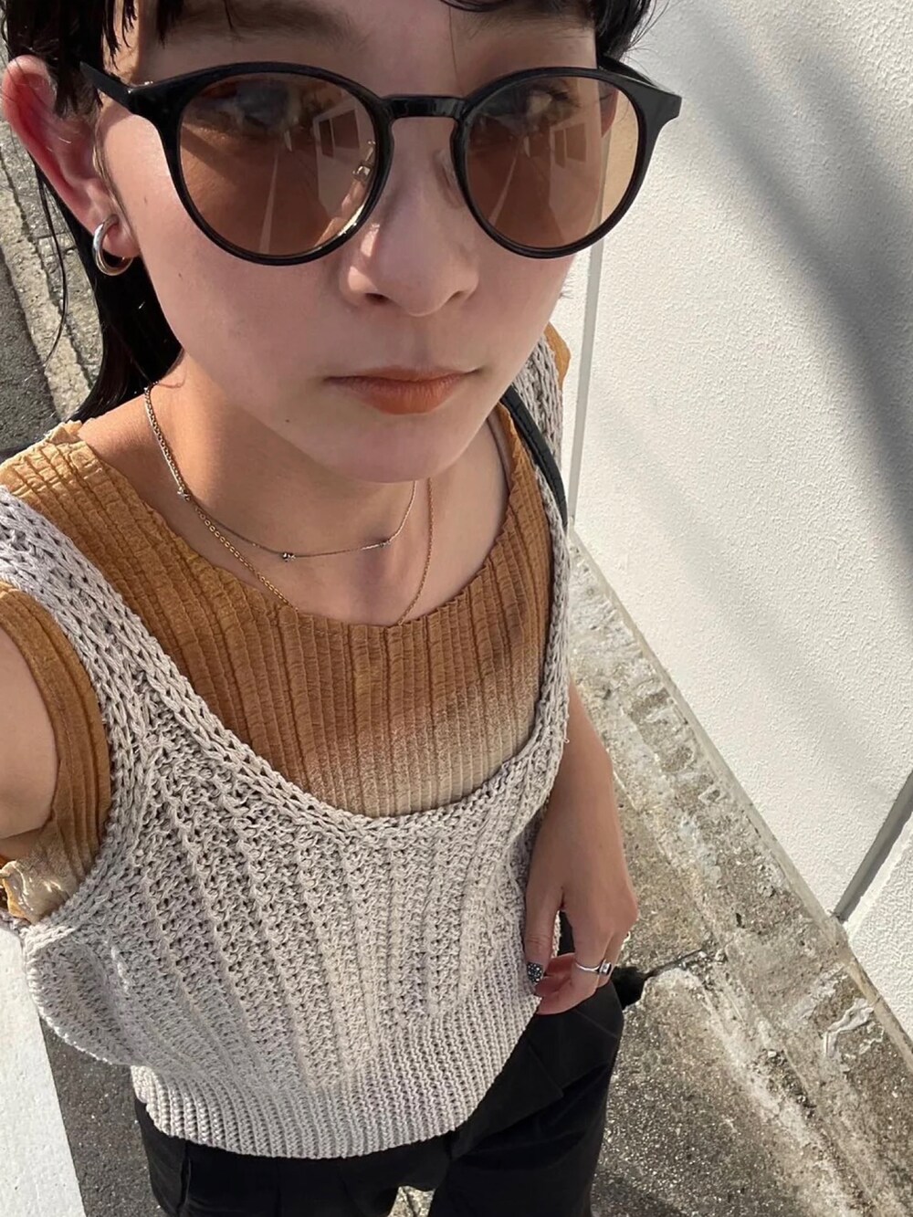 ホワイト系のベスト、ブラウン系のサングラスを着用したレディースの夏コーディネートの4枚目の写真