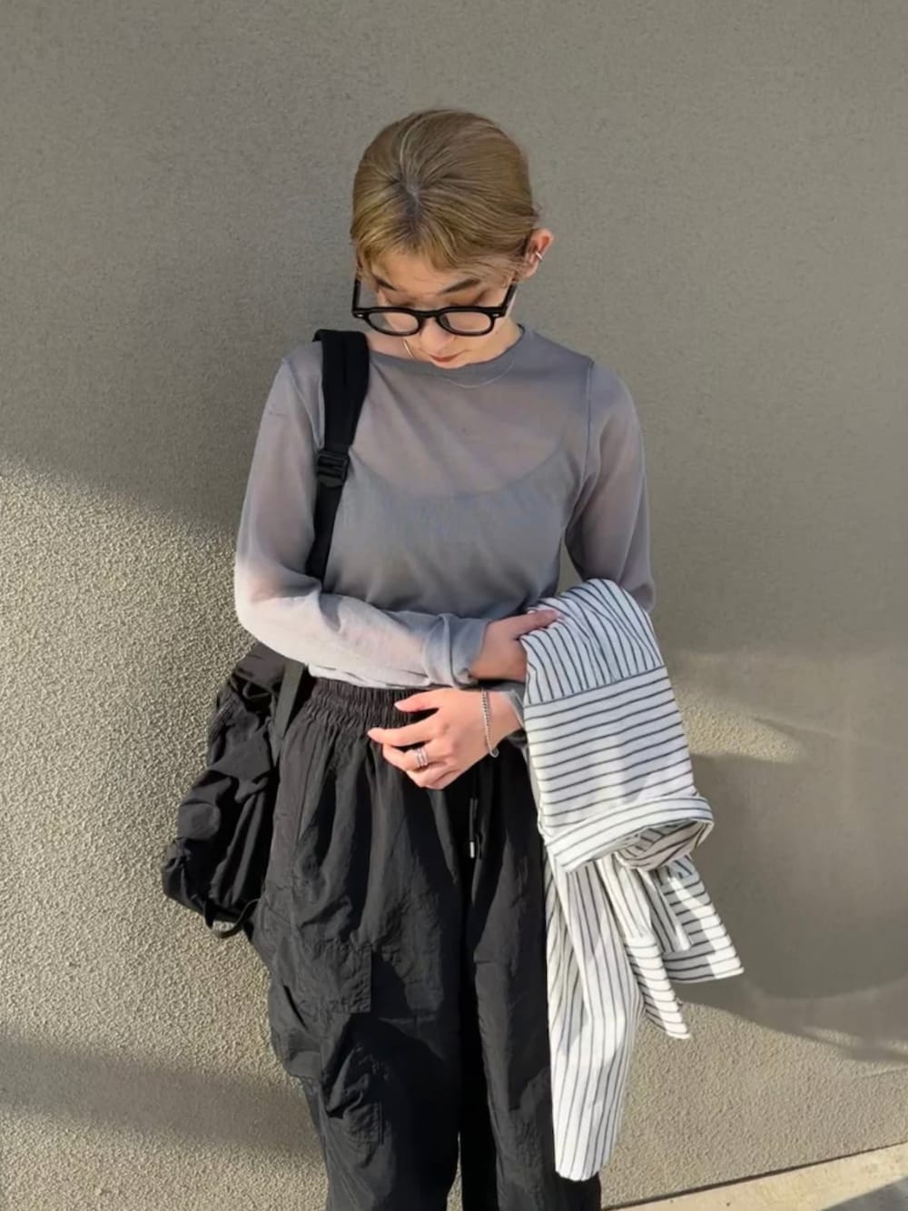 グレー系のニット/セーター、ホワイト系のシャツ/ブラウス、ブラック系のカーゴパンツを着用したレディースの春コーディネートの4枚目の写真