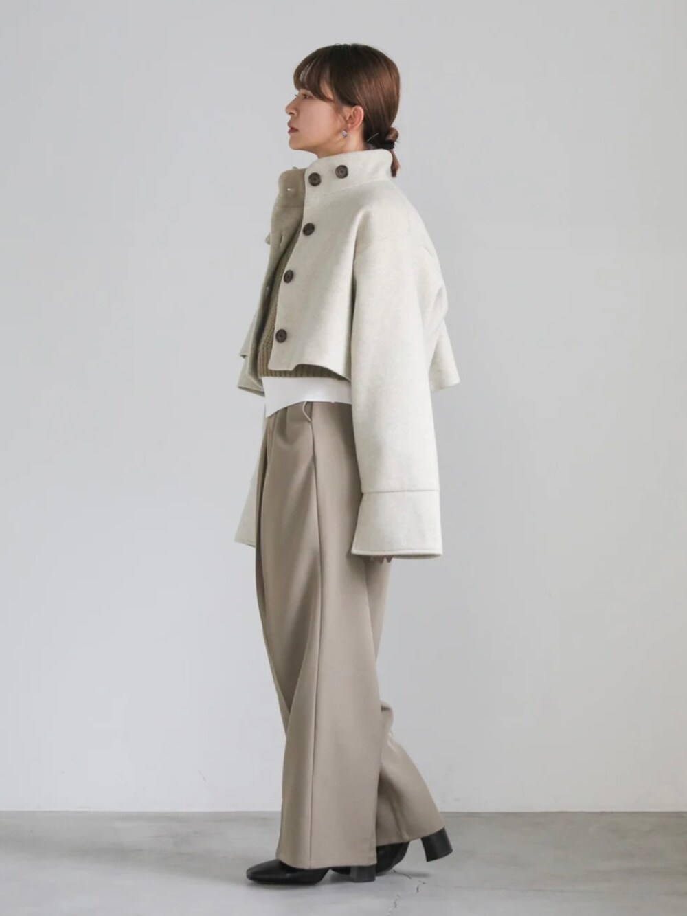 ベージュ系のステンカラーコート、ホワイト系のニット/セーター、グリーン系のベストを着用したレディースの冬コーディネートの5枚目の写真