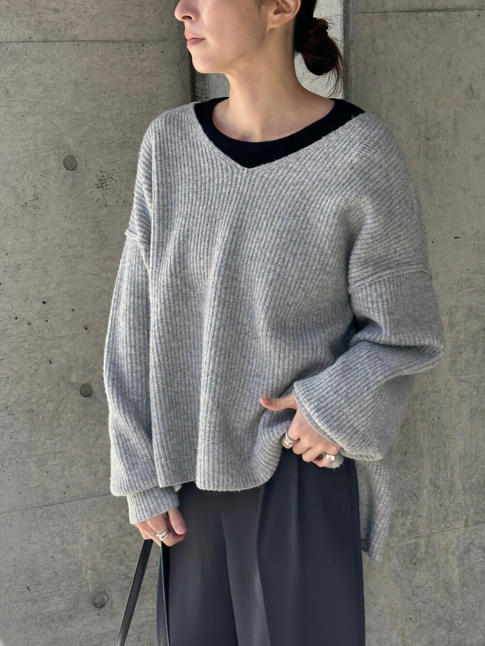 グレー系のニット/セーター、ブラック系のTシャツ/カットソー、グレー系のスラックスを着用したレディースの冬コーディネートの5枚目の写真