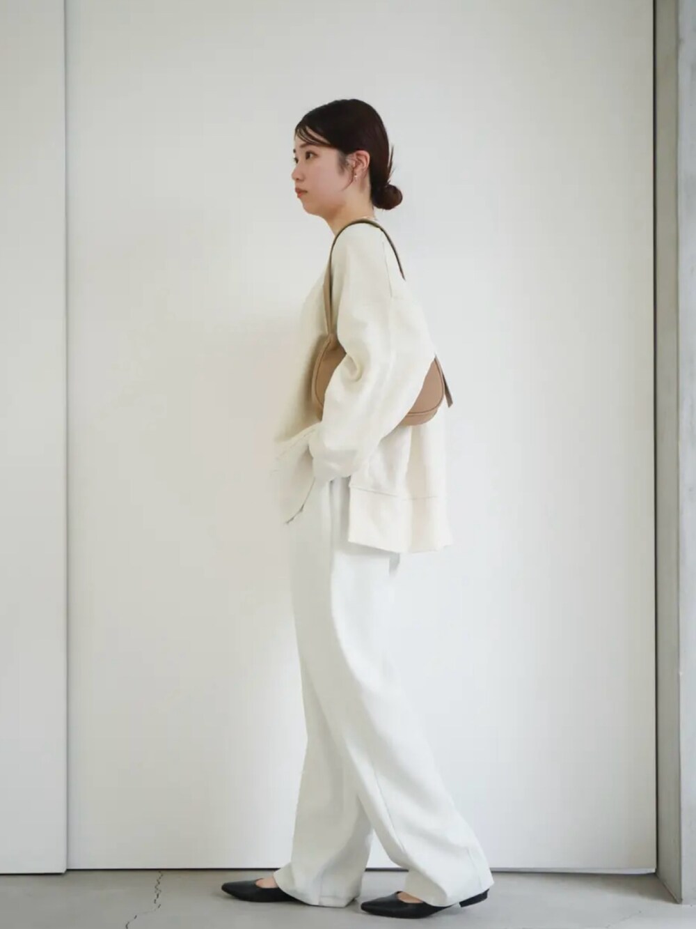 ホワイト系のスウェット、ホワイト系のスラックス、ベージュ系のショルダーバッグを着用したレディースの冬コーディネートの3枚目の写真