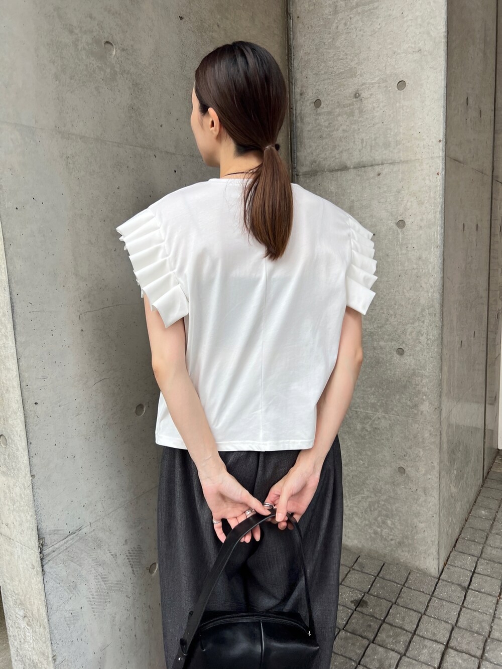 ブラック系のショルダーバッグ、ホワイト系のTシャツ/カットソー、グレー系のスラックスを着用したレディースの夏コーディネートの4枚目の写真