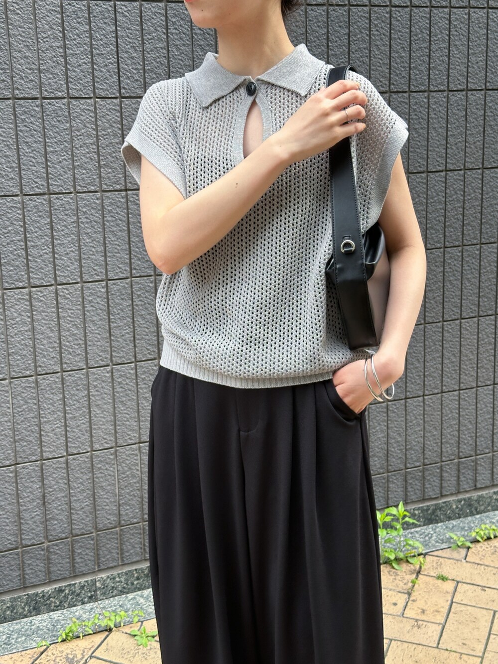 グレー系のニット/セーター、ブラック系のスラックス、ブラック系のショルダーバッグを着用したレディースの春コーディネートの2枚目の写真