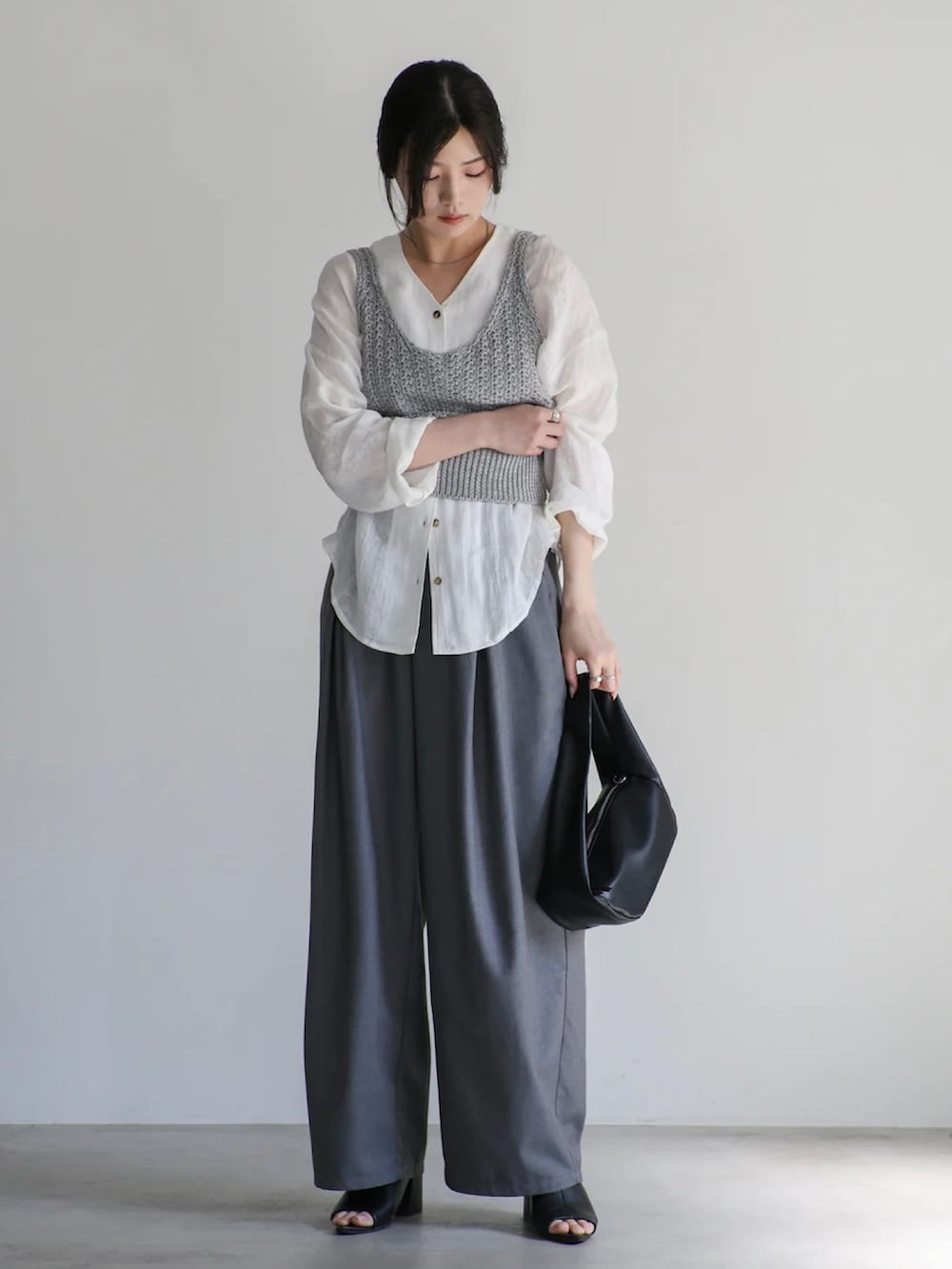 グレー系のベスト、ホワイト系のシャツ/ブラウス、グレー系のスラックスを着用したレディースの夏コーディネートの3枚目の写真