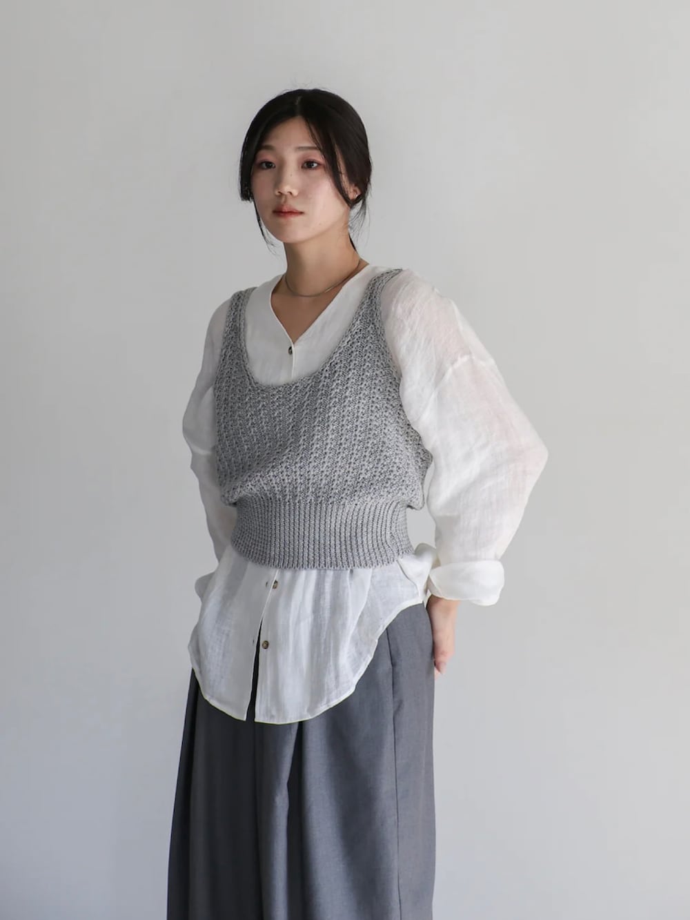 グレー系のベスト、ホワイト系のシャツ/ブラウス、グレー系のスラックスを着用したレディースの夏コーディネートの5枚目の写真