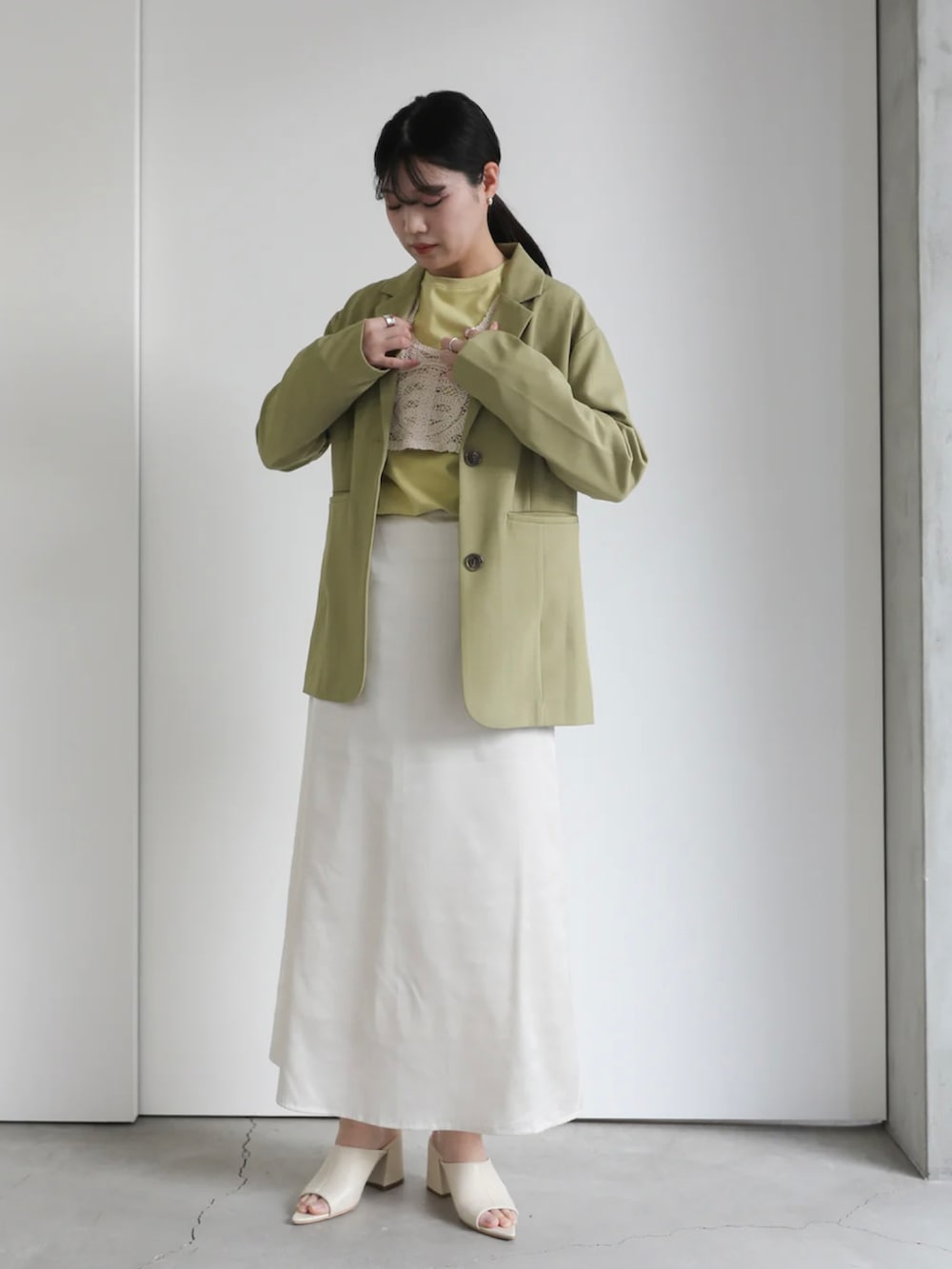 グリーン系のテーラードジャケット、ホワイト系のスカート、グリーン系のTシャツ/カットソーを着用したレディースの冬コーディネートの3枚目の写真