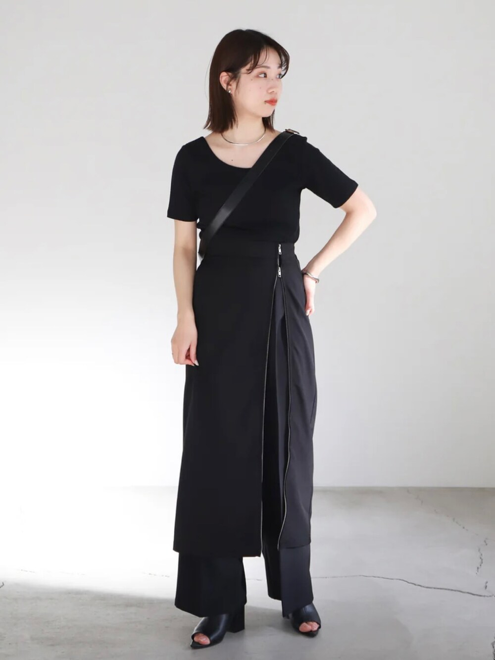 ブラック系のTシャツ/カットソー、ブラック系のスカート、ブラック系のスラックスを着用したレディースの春コーディネートの2枚目の写真