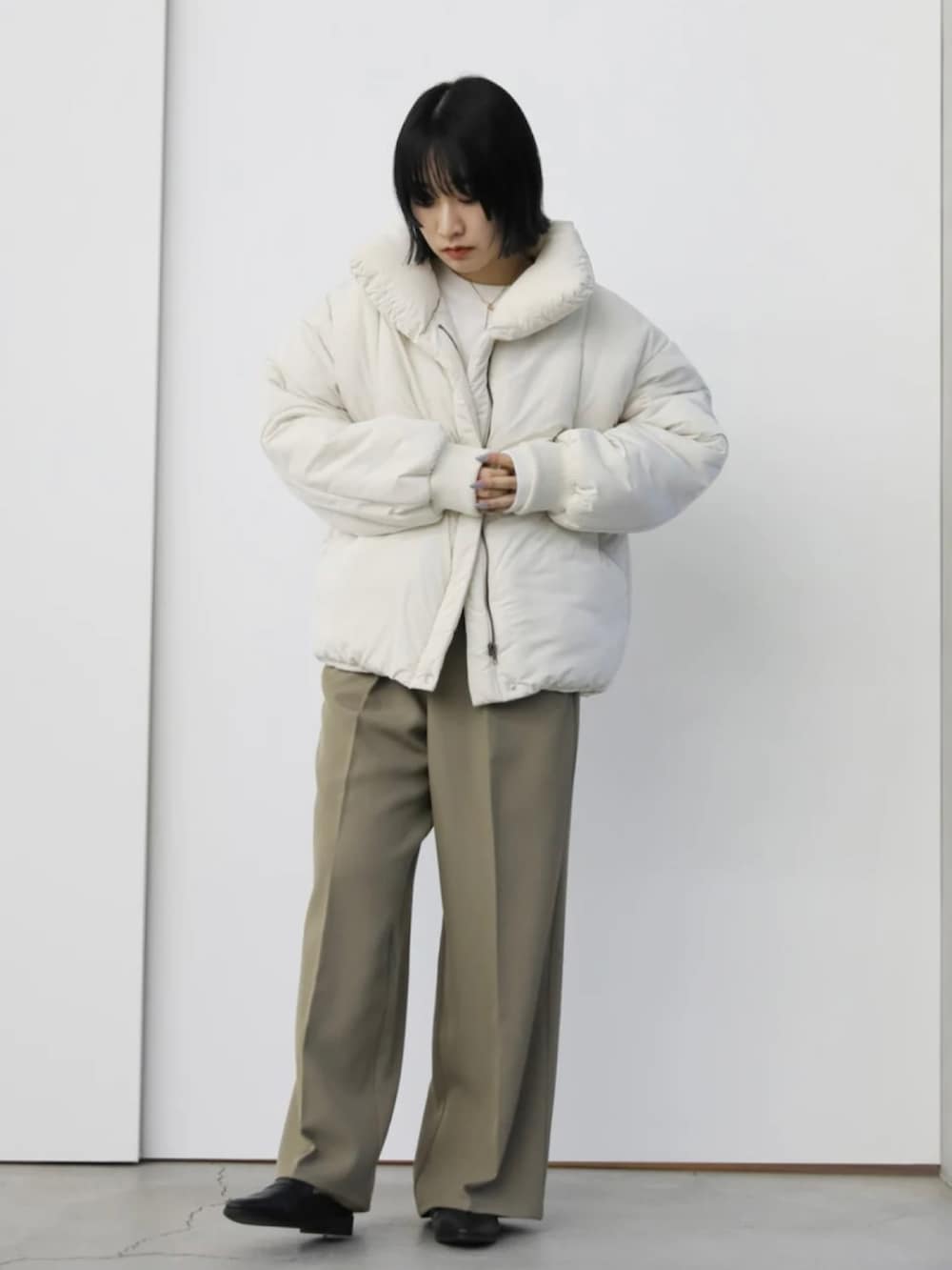 ホワイト系のダウンジャケット/コート、ベージュ系のスラックス、ホワイト系のニット/セーターを着用したレディースの秋コーディネートの4枚目の写真