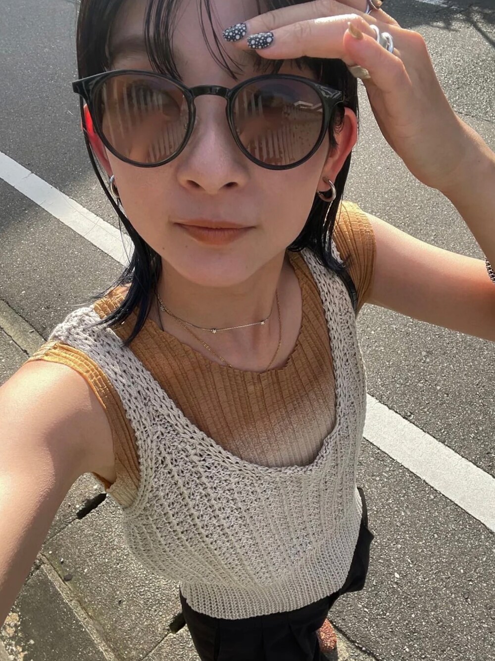 ホワイト系のベスト、ブラウン系のサングラスを着用したレディースの夏コーディネートの3枚目の写真