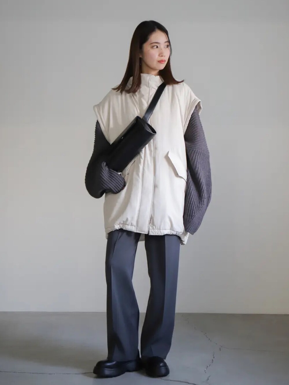 グレー系のニット/セーター、グレー系のスラックス、ホワイト系のダウンジャケット/コートを着用したレディースの冬コーディネートの3枚目の写真