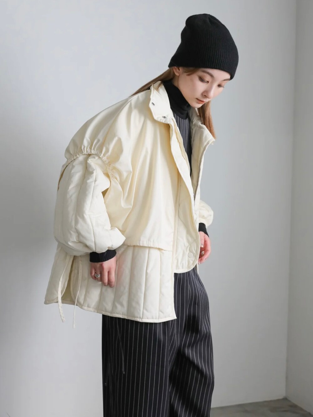 ホワイト系のダウンジャケット/コート、ブラック系のニットキャップ/ビーニーを着用したレディースの冬コーディネートの2枚目の写真