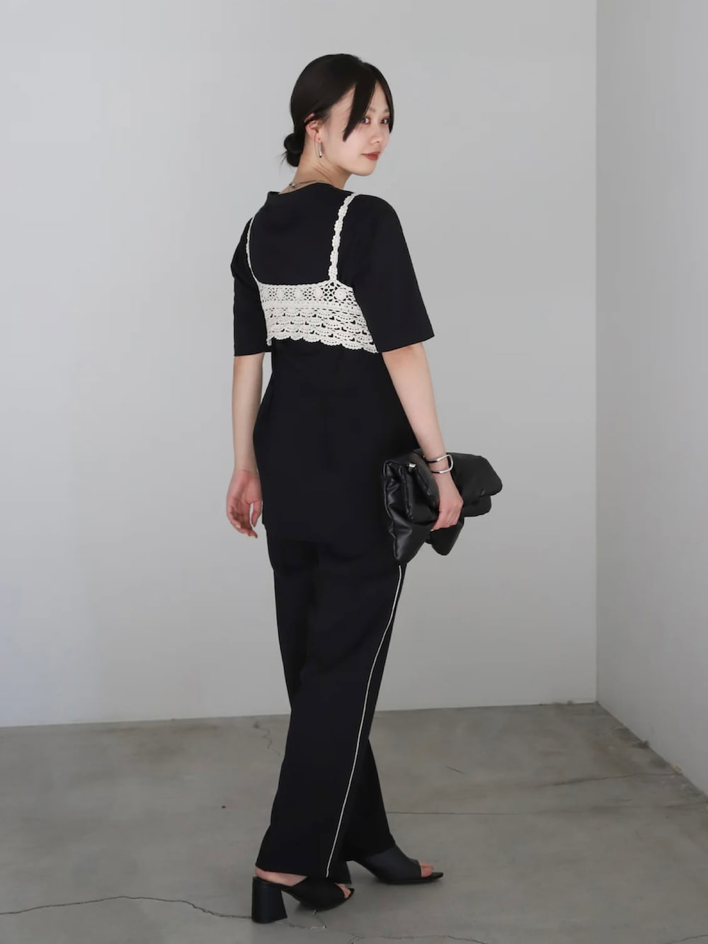 ブラック系のスラックス、ブラック系のサンダル、ブラック系のハンドバッグを着用したレディースの春コーディネートの4枚目の写真