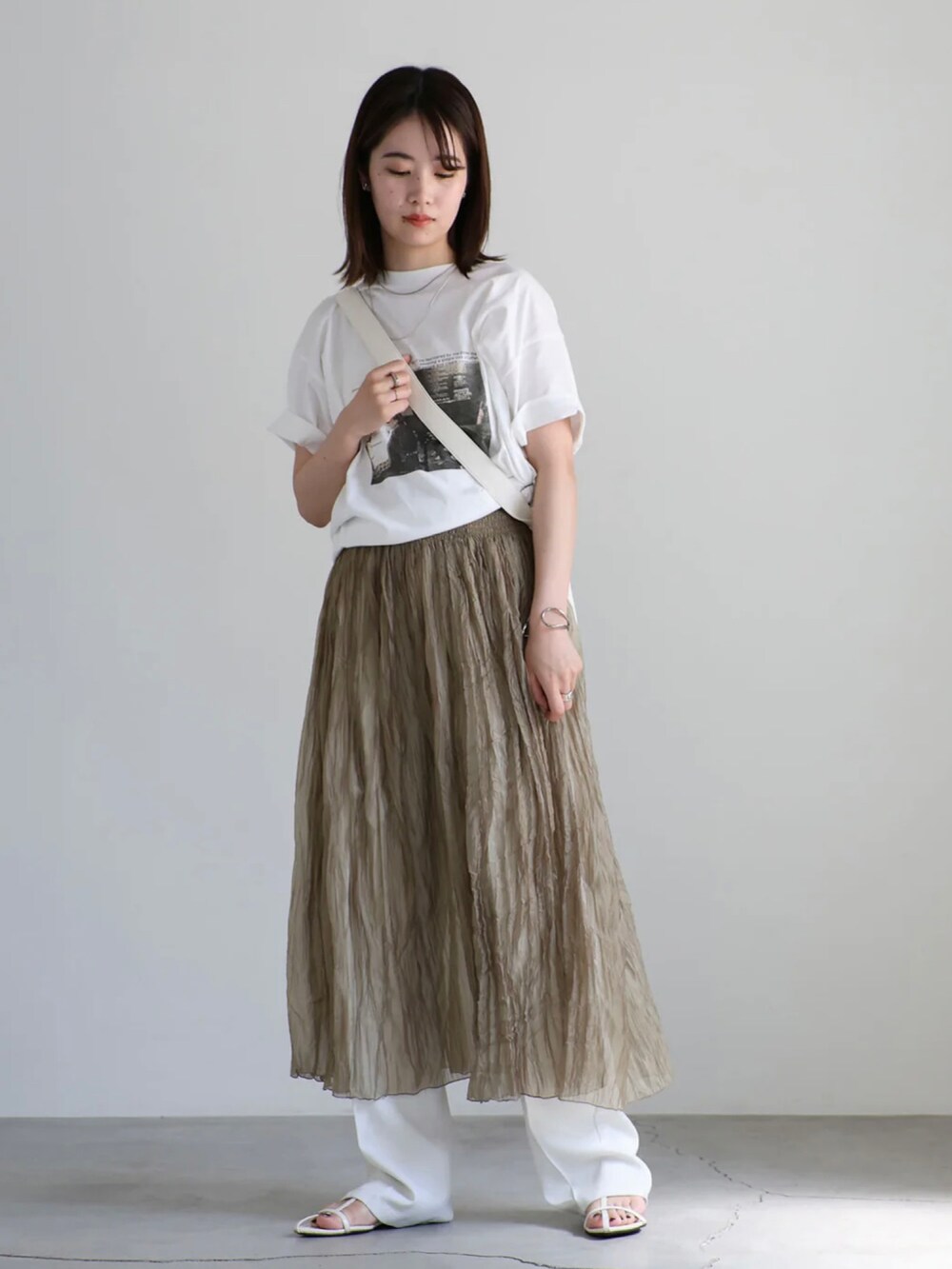 ホワイト系のTシャツ/カットソー、ホワイト系のスラックス、ブラウン系のワンピースを着用したレディースの夏コーディネートの3枚目の写真