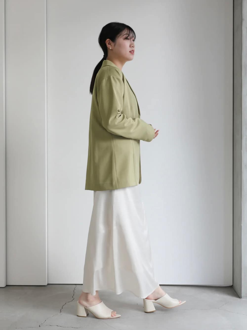 グリーン系のテーラードジャケット、ホワイト系のスカート、グリーン系のTシャツ/カットソーを着用したレディースの冬コーディネートの4枚目の写真