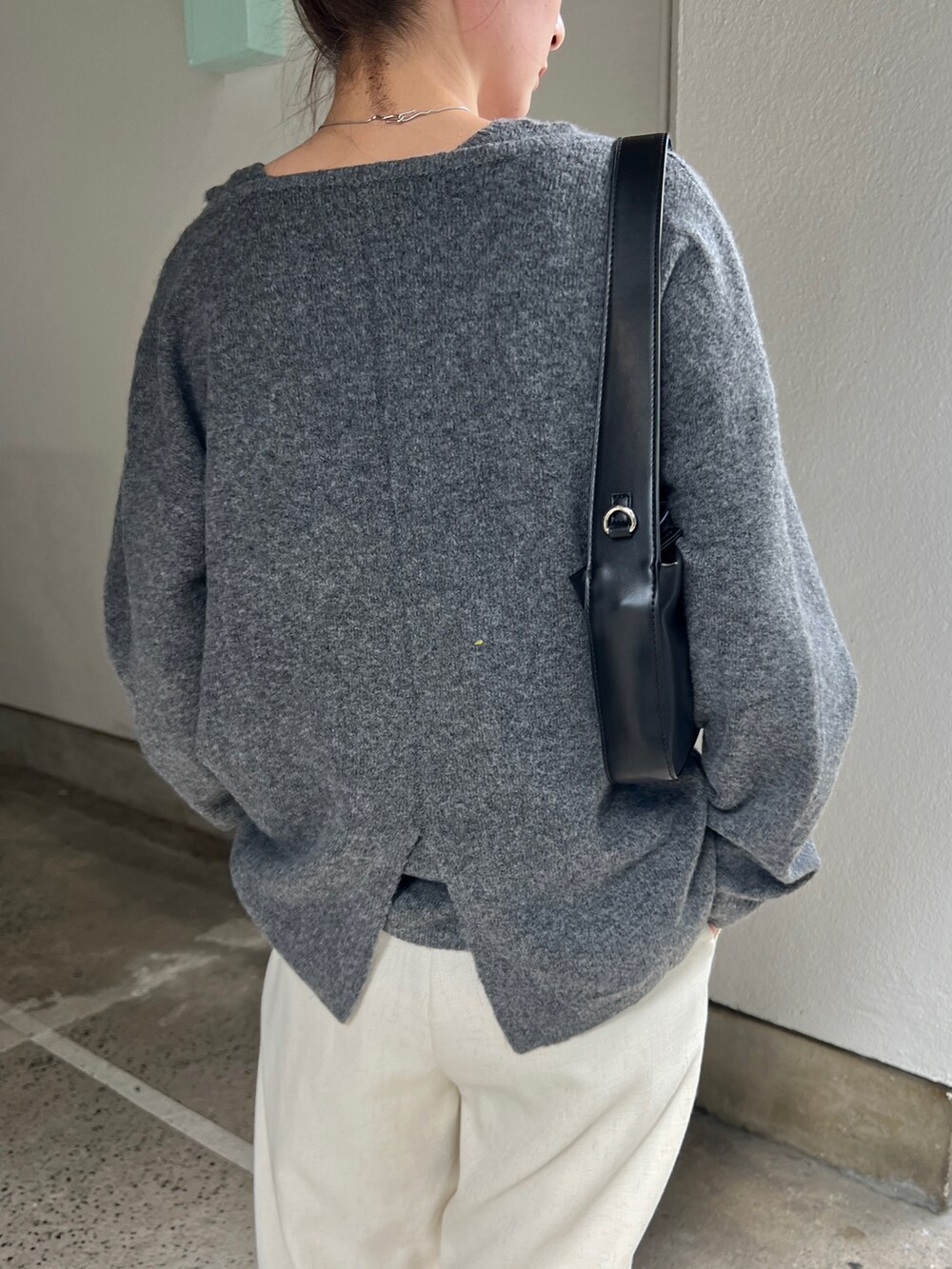 グレー系のニット/セーター、ベージュ系のスラックス、ブラック系のショルダーバッグを着用したレディースの秋コーディネートの5枚目の写真