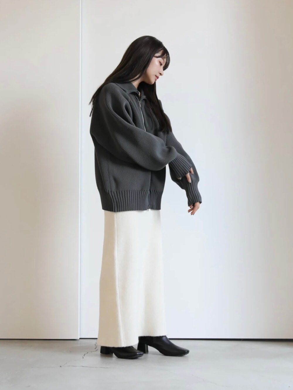 グレー系のニット/セーター、ホワイト系のスカートを着用したレディースの秋コーディネートの3枚目の写真