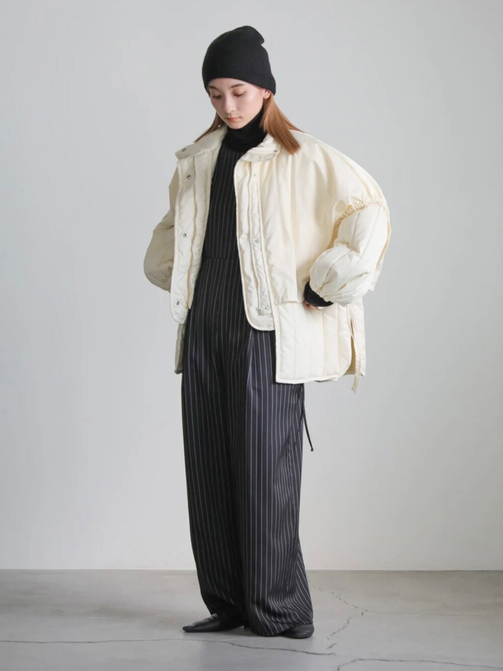 ホワイト系のダウンジャケット/コート、ブラック系のニットキャップ/ビーニーを着用したレディースの冬コーディネートの4枚目の写真