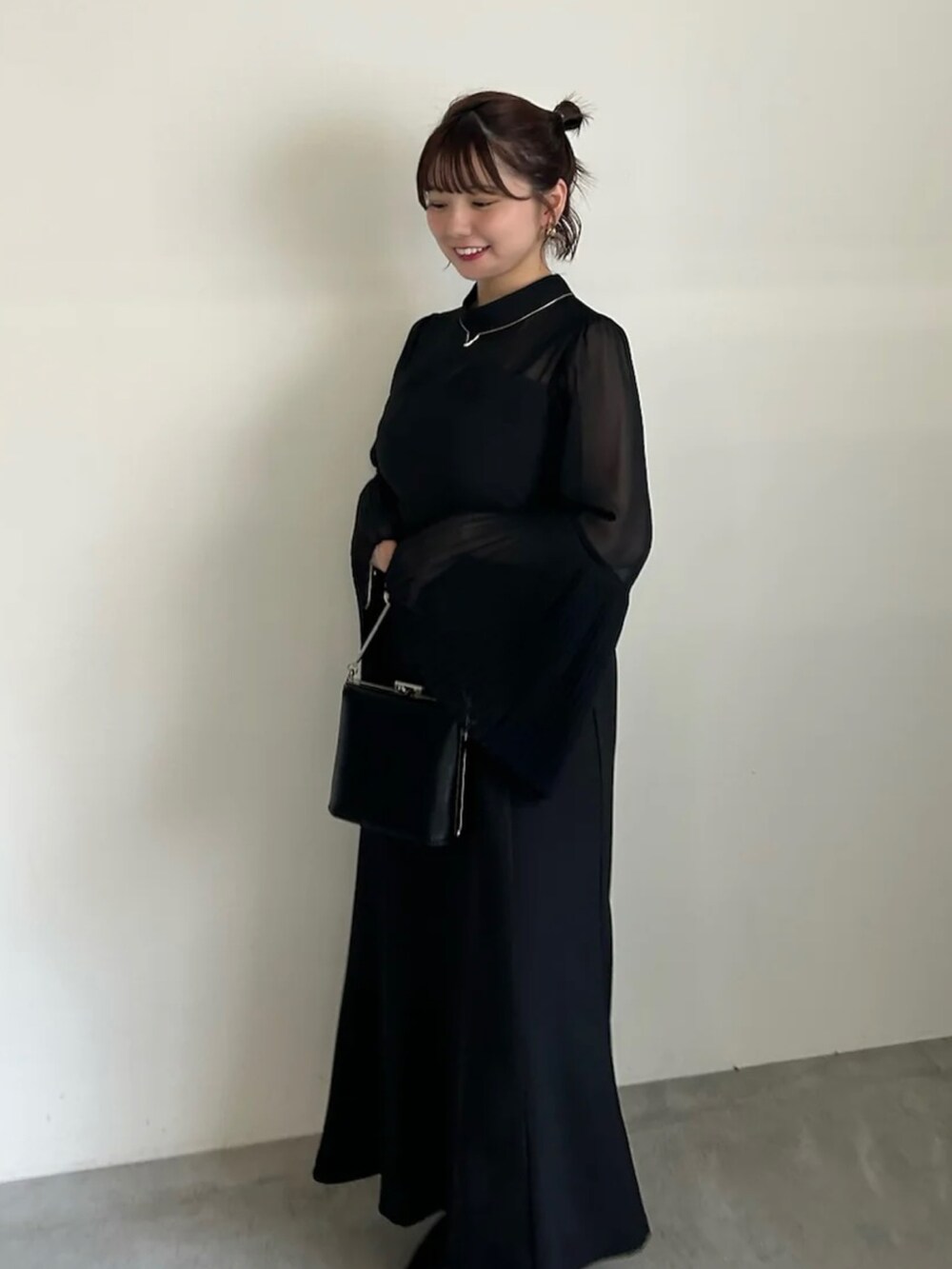 グレー系のワンピース、ブラック系のショルダーバッグ、ブラック系のパンプスを着用したレディースの春コーディネートの2枚目の写真