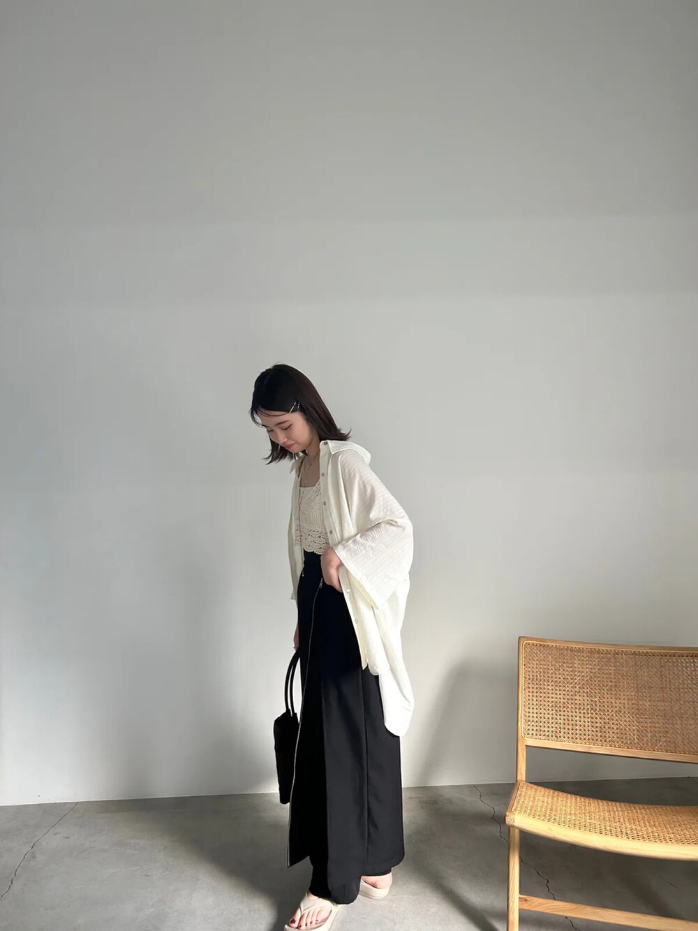 ブラック系のスカート、ホワイト系のベスト、グリーン系のキャミソールを着用したレディースの夏コーディネートの4枚目の写真