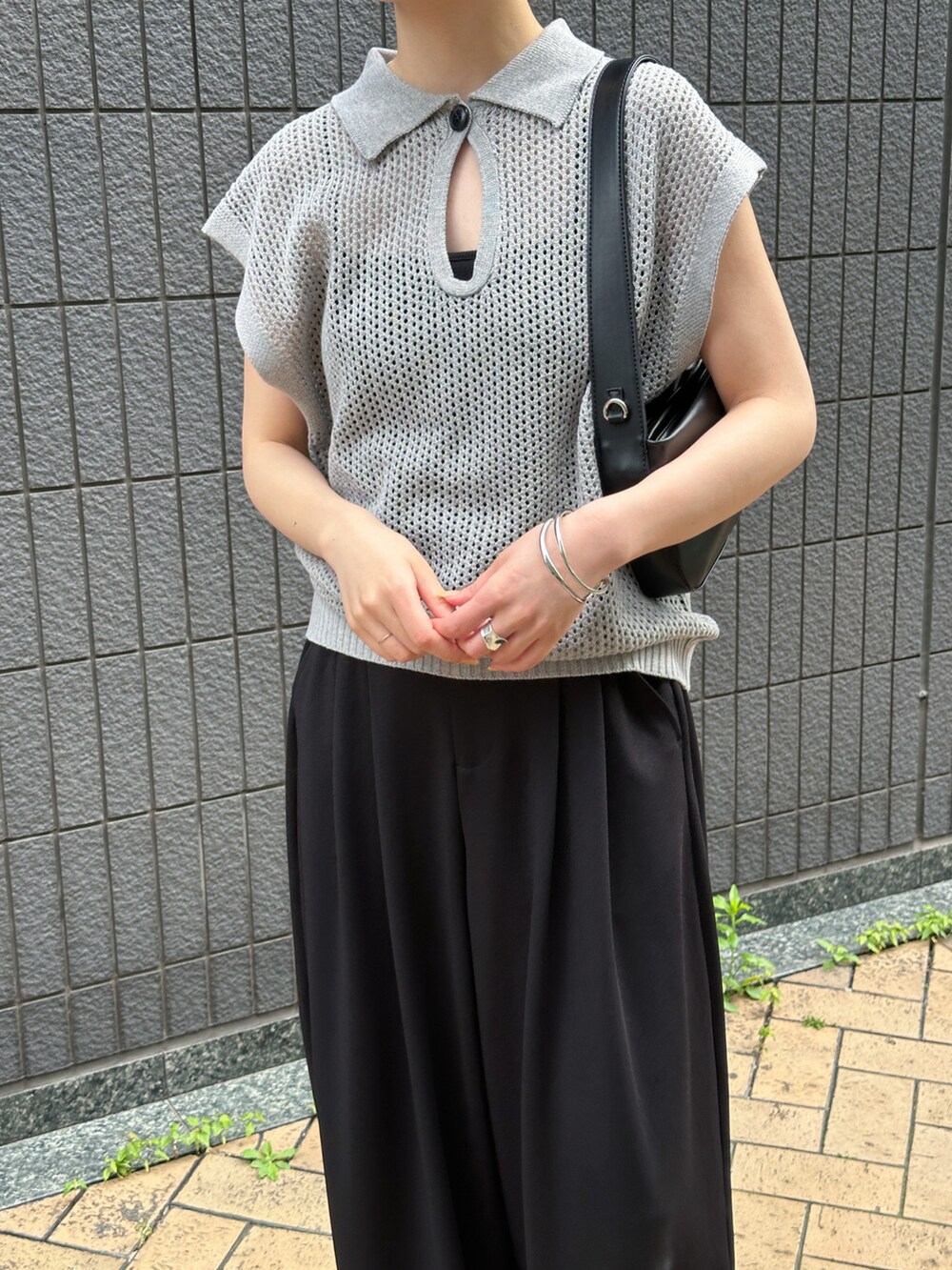 グレー系のニット/セーター、ブラック系のスラックス、ブラック系のショルダーバッグを着用したレディースの春コーディネートの3枚目の写真