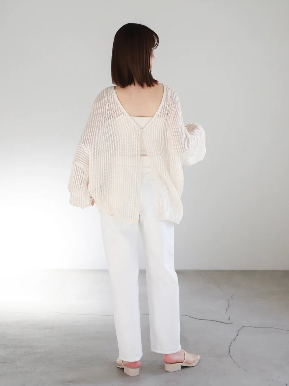 ホワイト系のカーディガン/ボレロ、ホワイト系のキャミソール、ゴールド系のネックレスを着用したレディースの春コーディネートの2枚目の写真