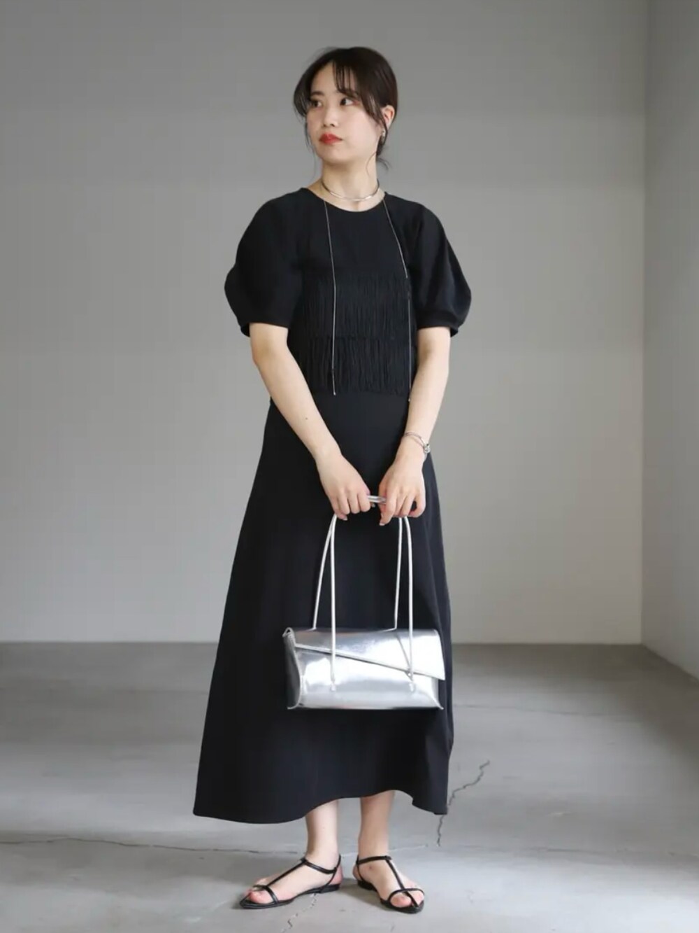 ブラック系のワンピース、シルバー系のハンドバッグ、シルバー系のネックレスを着用したレディースの夏コーディネートの2枚目の写真