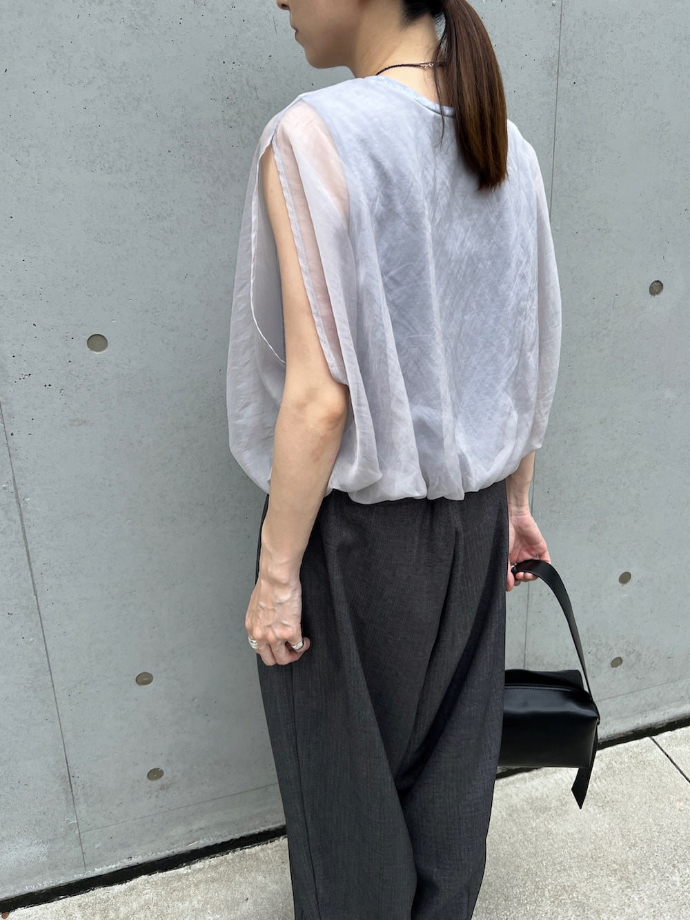 グレー系のシャツ/ブラウス、ブラック系のショルダーバッグ、グレー系のスラックスを着用したレディースの夏コーディネートの4枚目の写真