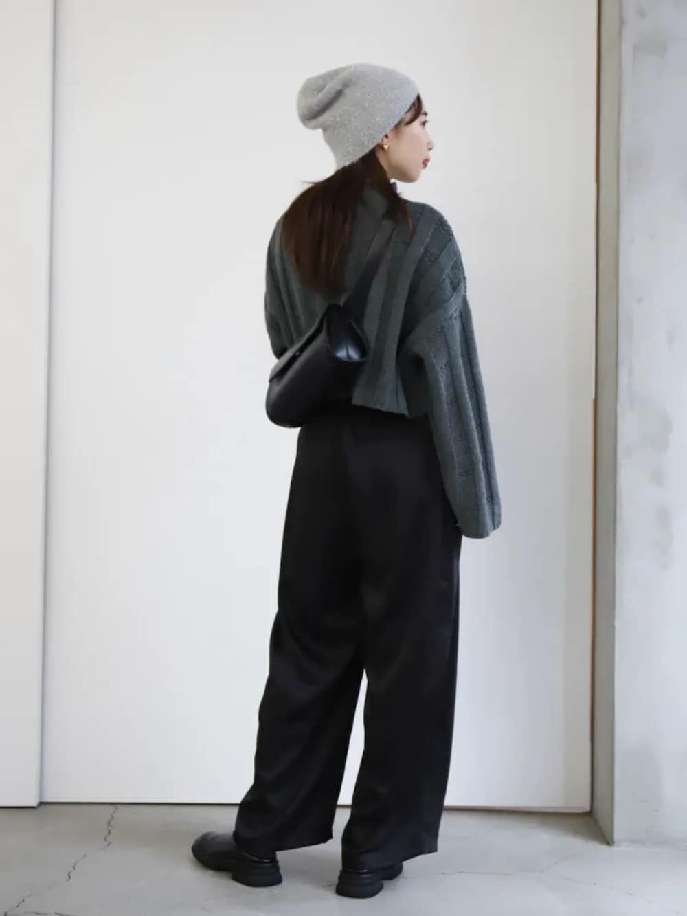 ブラック系のスラックス、ブラック系のショルダーバッグ、グレー系のニット/セーターを着用したレディースの冬コーディネートの2枚目の写真