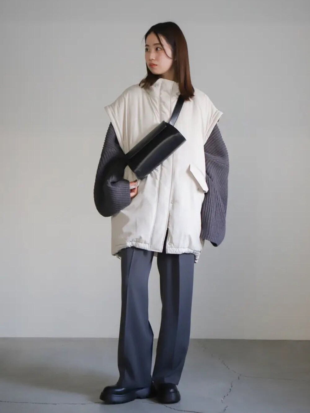 グレー系のニット/セーター、グレー系のスラックス、ホワイト系のダウンジャケット/コートを着用したレディースの冬コーディネートの5枚目の写真