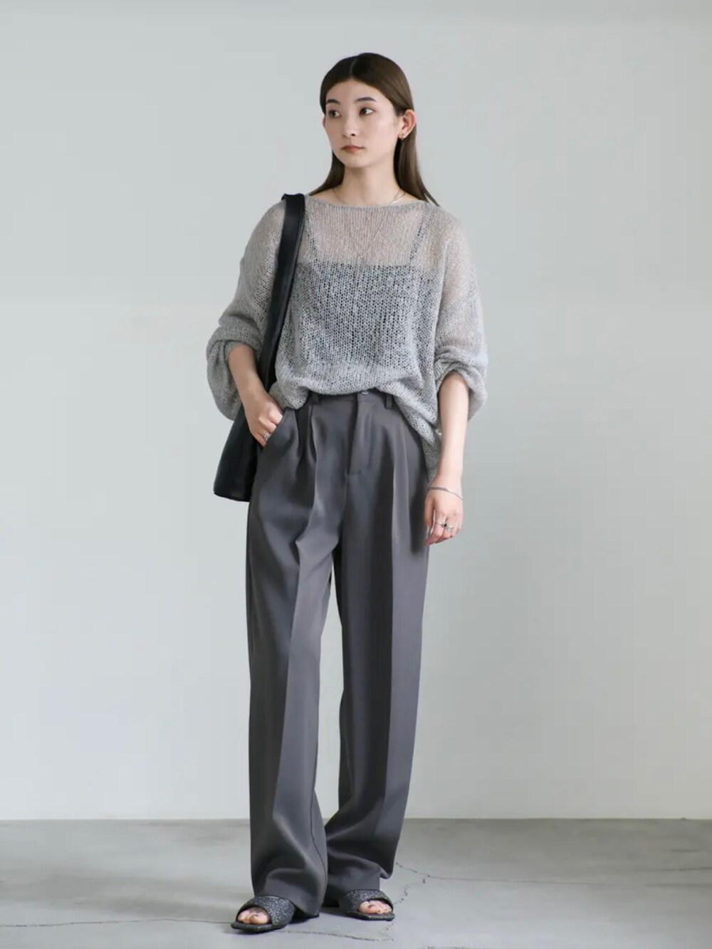 グレー系のニット/セーター、グレー系のスラックス、ブラック系のサンダルを着用したレディースの夏コーディネートの2枚目の写真