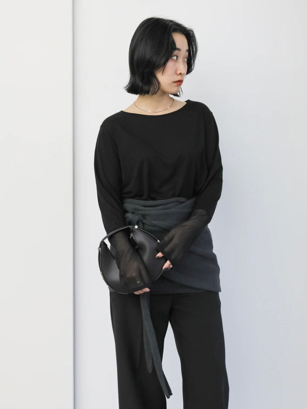 ブラック系のTシャツ/カットソー、ブラック系のハンドバッグ、ブラック系のサンダルを着用したレディースの冬コーディネートの5枚目の写真