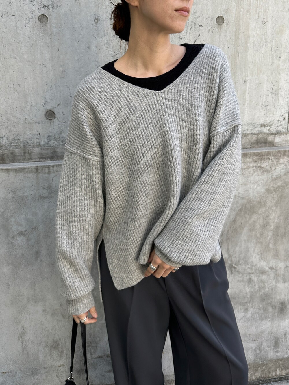 グレー系のニット/セーター、ブラック系のTシャツ/カットソー、グレー系のスラックスを着用したレディースの冬コーディネートの4枚目の写真