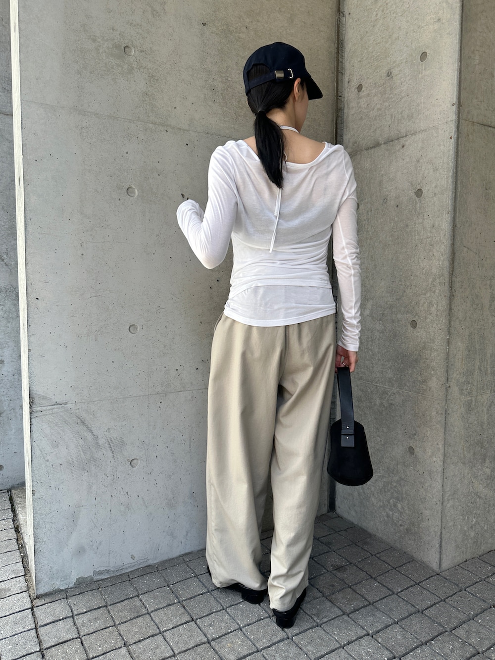 ホワイト系のTシャツ/カットソー、ブラック系のハンドバッグ、ベージュ系のスラックスを着用したレディースの秋コーディネートの3枚目の写真